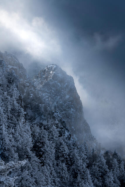 Sunlight penetrates heavy cloud cover during a winter storm in the Sandia Mountains of New Mexico