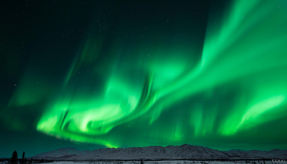 The aurora borealis illuminates the Granite Range of Alaska in this night photograph. 