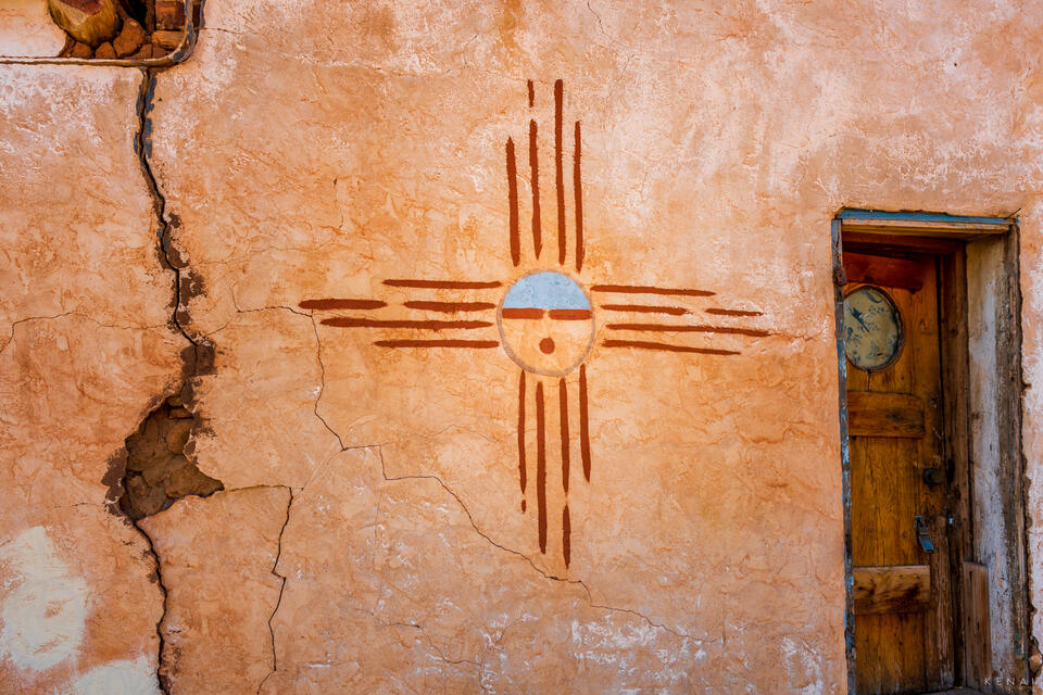 An old adobe house is decorated with stylized Zia symbol in New Mexico. 
