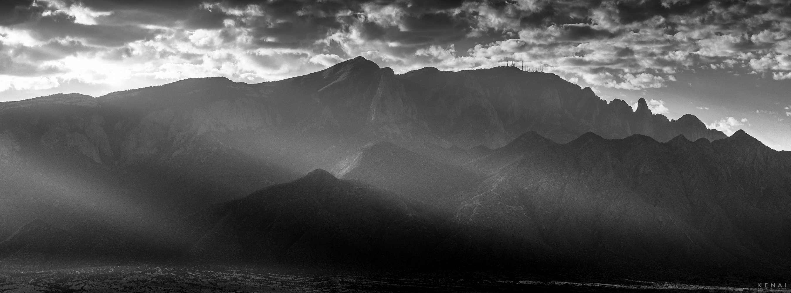 North Sandia Mountains illuminated by early morning sun rays in this black and white landscape photo. 